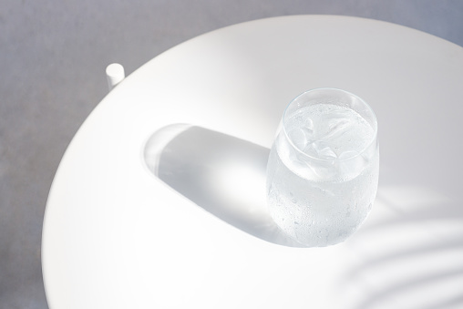 a glass of water with ice on white table.