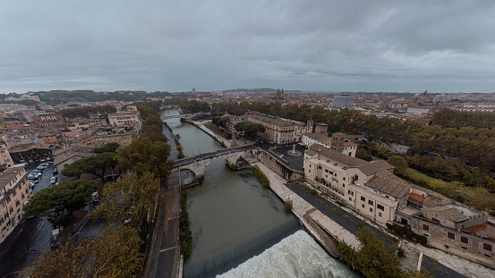 Aerial drone view of porte Cestio, a three arch bridge connecting isle of Tiberina to the land, spanning across the river Tiber. Autumn setting, other bridges visible in the background.