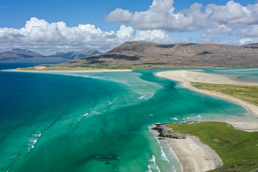 An aerial drone view of Luskentyre beach, on the Isle of Harris in the Outer Hebrides, on the northwest Atlantic coastline of Scotland. Taken from Seilebost, the image captures the stunning seascape on a sunny summer day. The turquoise and aquamarine blue seas and white sandy beaches make it one of Scotland's most iconic and favourite destinations.