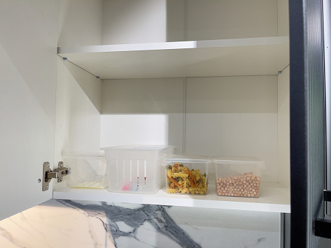 Open cupboard with cereal in plastic containers. Storage system.