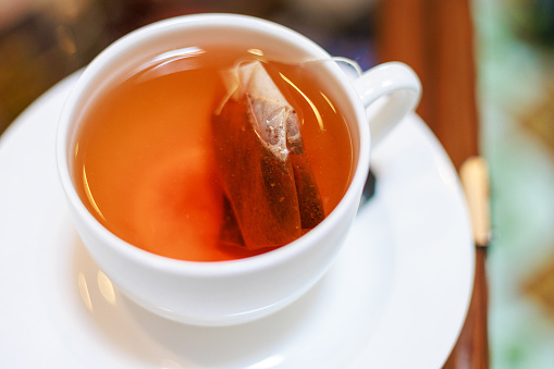 Dipping tea bag in a cup of hot water.