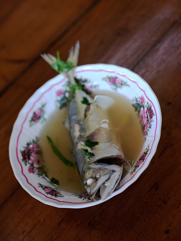 Thai street food ,  clear spicy hot & sour soup (Tomyum) with boiled asian red tail cat fish fillet and herb .