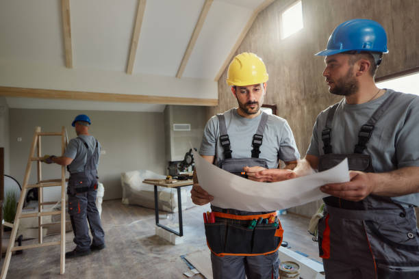istock Manual workers analyzing blueprints at renovating house. 1829915327