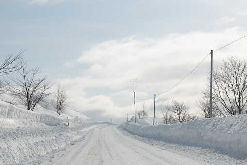 A cleared snow covered road with deep snow either side, Hokkaido