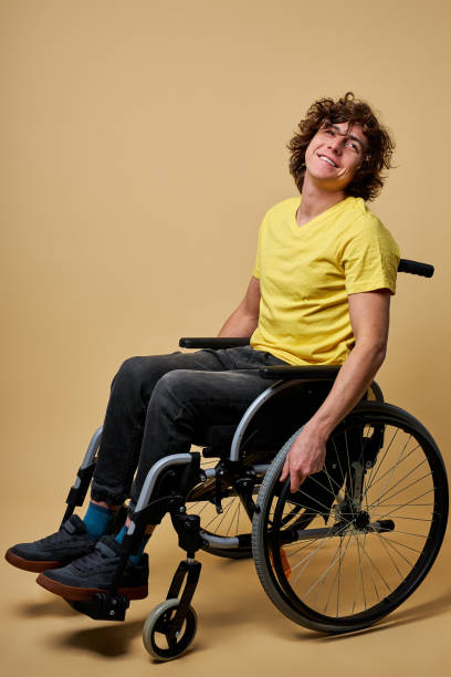 new start. handicapped positive young man touching wheels and sitting in profile while moving ahead - physical injury men orthopedic equipment isolated on white imagens e fotografias de stock