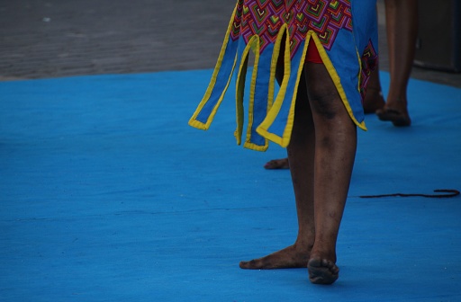 A group of excited African folk dancers, wearing traditional clothing, performing a vibrant dance