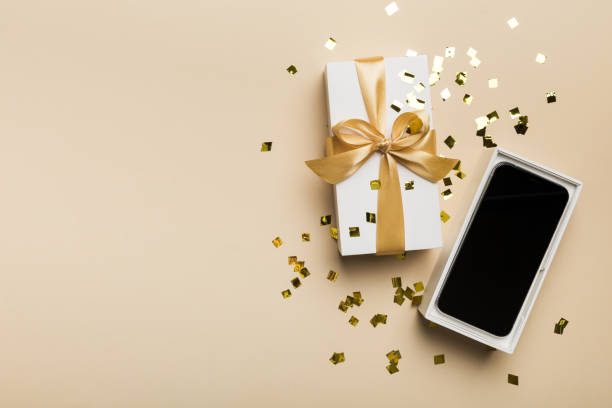 istock Opened gift box with gold ribbon and smartphone on color background, top view. Blank open box packaging mockup , Template for your design - branding mockup 1829984796