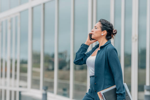 istock business woman walking talking on mobile phone 1829987572