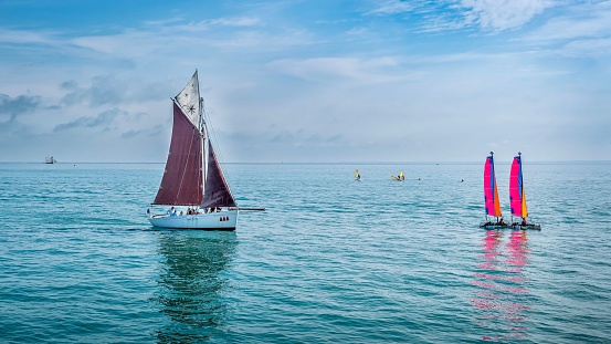 A group of sails boats gliding peacefully on the bright blue ocean in Cancale, France