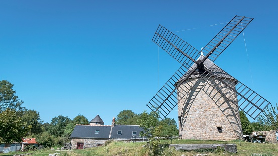 A picturesque stone windmill under a bright blue sky in Mont Dol, France