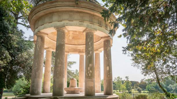 istock Tranquil stone gazebo surrounded by tall trees in Paris, France 1829990749