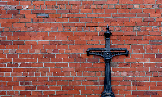 Metal Cross on Red Brick Wall.