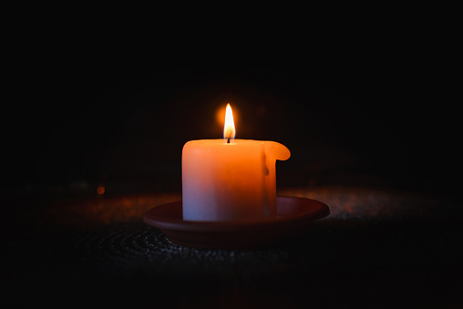 A burning candle.Bright light on dark background.RIP darkness template. lighting a candle in the darkness.Copy space.