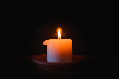 A burning candle.Bright light on dark background.RIP darkness template. lighting a candle in the darkness.
