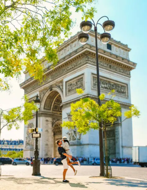 Couple on a citytrip in Paris visiting Avenue des Champs Elysees Paris France Arc De Triomphe. Men and women visiting the Arc de Triomphe in Paris