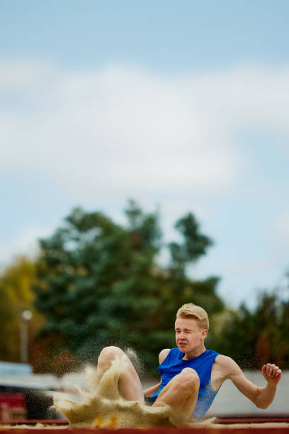 istock Sand pit marks the landing point of athletic feat in progress. Athletic man, professional sportsman sets new long jump record. 1830046682
