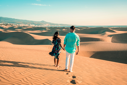 couple walking at the beach of Maspalomas Gran Canaria Spain, men and woman at the sand dunes desert of Maspalomas Spain Europe during vacation