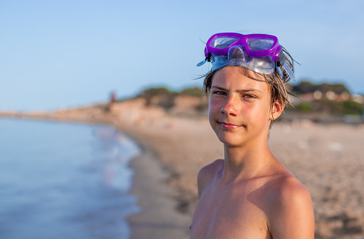 A handsome teenager wears a diving mask, radiating happiness during a carefree day at the summer beach,copyspace.