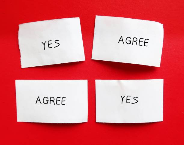 Pieces of paper on red background with words YES and AGREE- concept of Groupthink - phenomenon occurs when group reaches consensus without critical reasoning or evaluation but based on common desire not to upset group pedazos de papel sobre fondo rojo con las palabras sÍ y de acuerdo- concepto de pensamiento grupal - fenómeno que ocurre cuando el grupo llega a un consenso sin razonamiento crítico o evaluación, sino basado en el deseo común de no molestar al grupo