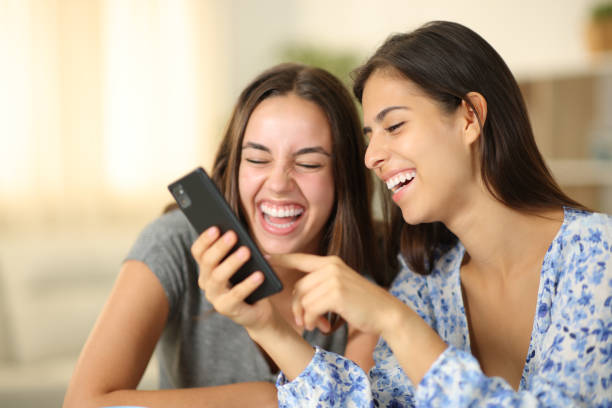 istock Two joyful roommates laughing watching media on phone 1830059145
