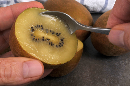 Eating a yellow kiwi with a spoon close-up