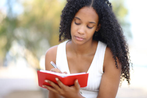 Black woman writing in agenda on the beach