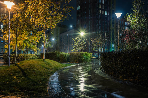 istock Night park paths and colored houses on a rainy autumn night. Night paths, benches, lanterns in a beautiful residential complex. Night autumn park with lanterns, benches, yellow leaves. Kyiv. Ukraine 1830067276