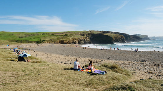 Gunwalloe, United Kingdom - October 10th, 2023: Tourists and locals enjoying late summer sunshine on Church Cove, Gunwalloe beach on the Lizard Peninsula, Cornwall, UK. Gunwalloe is one of the most southerly beaches in the UK and enjoys an exceptional mild climate.