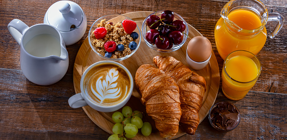 Breakfast served with coffee, orange juice, egg, cereals and croissants.