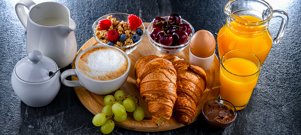 Breakfast served with coffee, orange juice, egg, cereals and croissants.