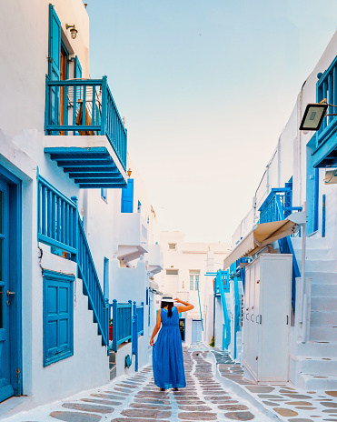 Mykonos Greece, Little Venice Mykonos Greece, Asian woman in a blue dress walking at the street of sunset at ocean fron at Mykonos town Europe