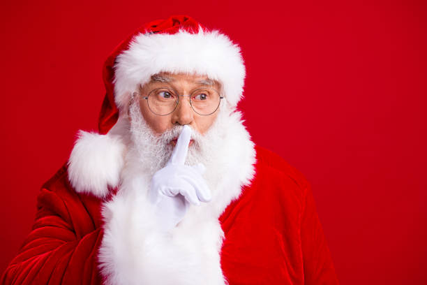 Photo of kind jolly santa claus wear white gloves hand touch lips showing gesture dont say anything isolated on red color background Photo of kind jolly santa claus wear white gloves hand touch lips showing gesture dont say anything isolated on red color background. santa claus expressions shhh stock pictures, royalty-free photos & images