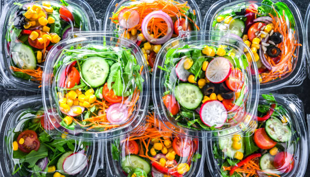 Boxes with pre-packaged vegetable salads in a commercial fridge