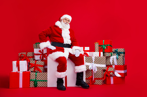 Photo of fairy character old santa claus sitting on cube pile stack gifts festal christmas time isolated on red color background year.