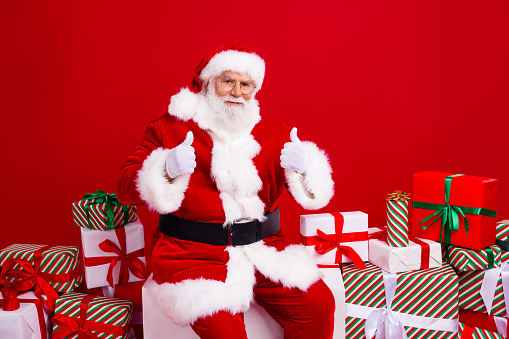 Photo of satisfied cheerful man santa claus wear hat glasses white gloves thumbs up sale discount isolated on red color background year.