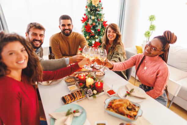 istock Friends making a toast and drinking wine while having Christmas dinner at home 1830113379