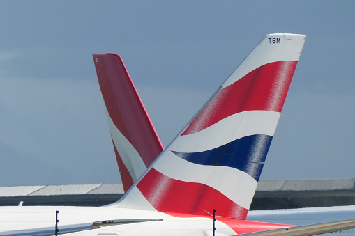 The vertical stabilisers of planes heading to London via Singapore prepare to depart from Sydney Kingsford-Smith Airport.  On the right is a British Airways Boeing B777-300(ER) plane, registration G-STBM and departing as flight BA16.  On the right is a Qantas A380-842, registration VH-OQD and departing as flight QF1.  The British Airways plane departed first and arrived in London 30 minutes before Qantas. The journey from Sydney to London is known as the \