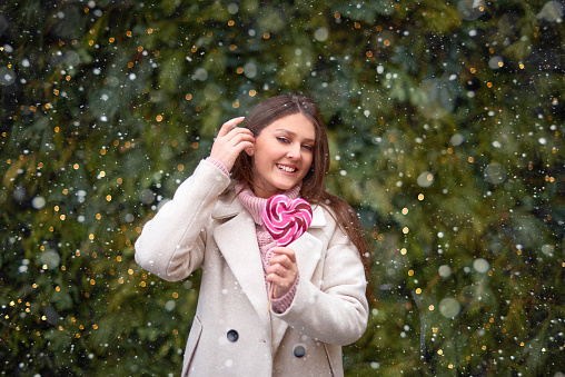 woman in love walk and eat red heart-shape lolly-pop on stick. valentine's day concept