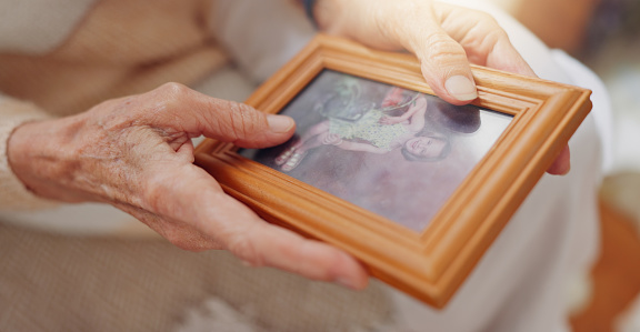 Frame, picture and hands of senior person for nostalgia, memories and thinking of past in home. Retirement home, elderly and closeup of photo to remember, mourning and depression with Alzheimer's