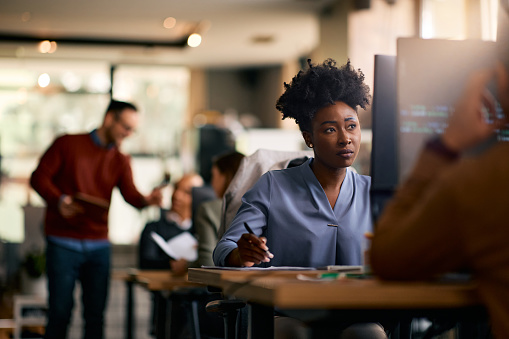 African American female graphic designer working on computer in the office.