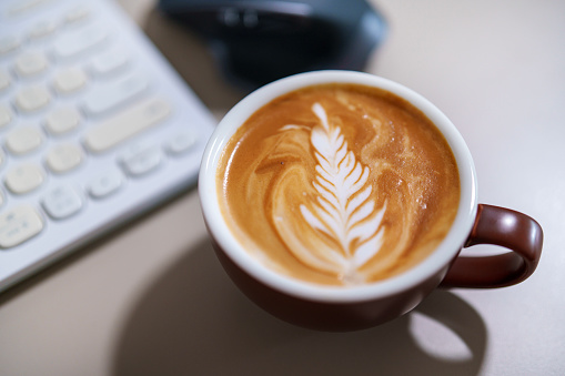 A still life moment of of a cup coffee latte sits alone in a home office space