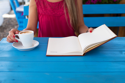 Young woman student sitting and drinking coffee and reading a book