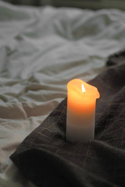 istock a lit candle sitting on a blanket thats covered in wrinkled blankets 1830182653