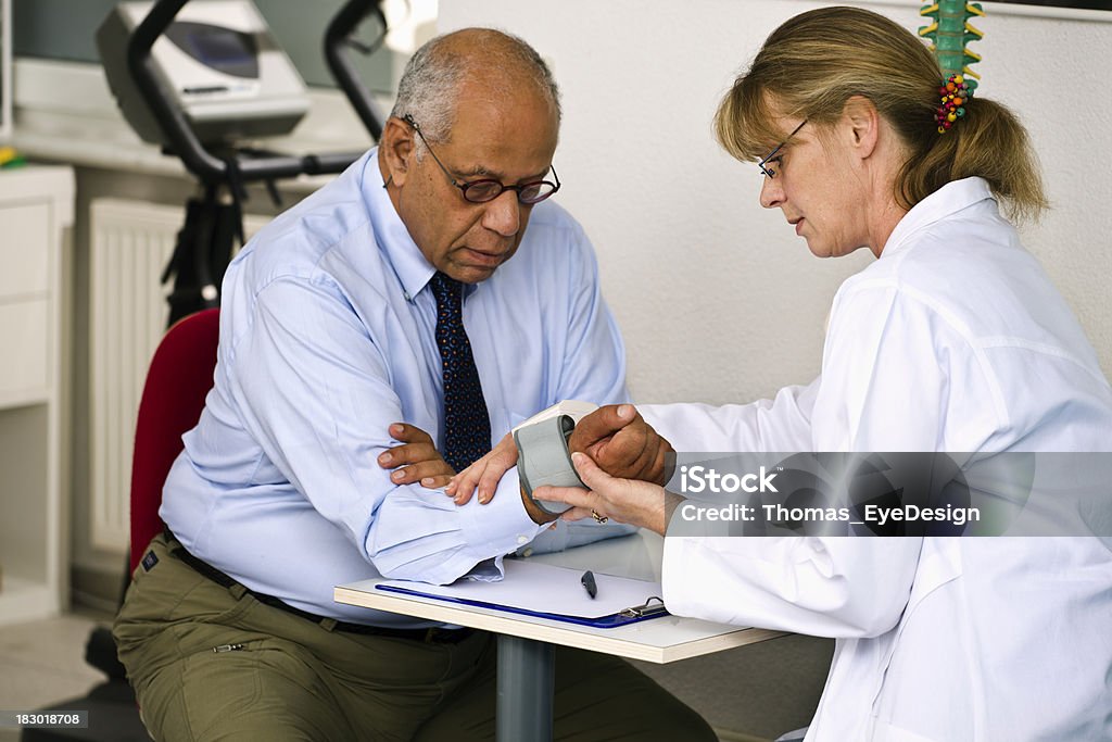 Doctor revisando la presión sanguínea de su paciente - Foto de stock de Indicador de presión sanguínea libre de derechos