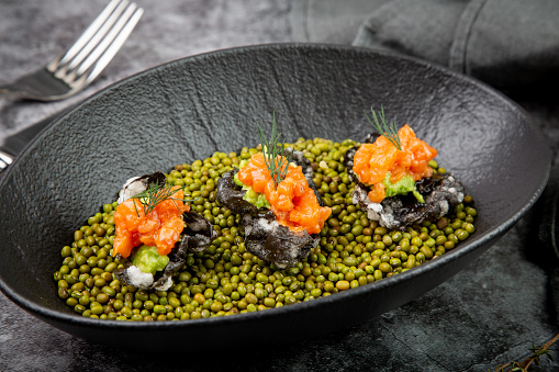 black caviar, red fish and wassabi on a plate with peas, top view