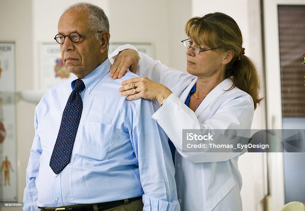 Médico examina el hombro de la paciente - Foto de stock de Accesorio para ojos libre de derechos