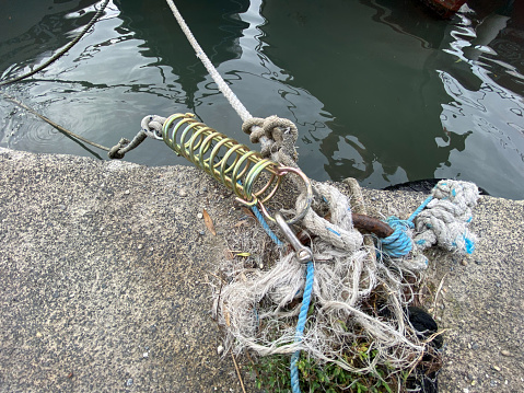 Rope attached to the bollard in the port with a modern iron boat docking spring. Fishermans equipment. anchor hardware