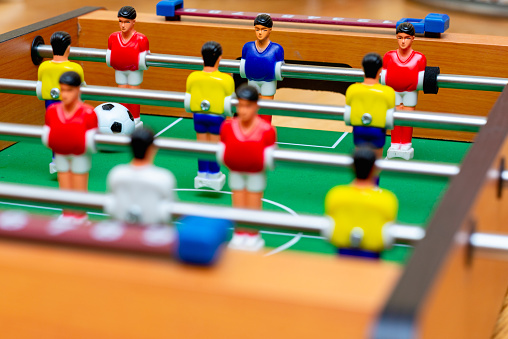 Close up table soccer with red yellow players and a ball.