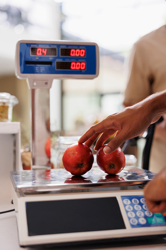 In an eco-friendly store, an electronic scale is used to weigh organic produce grown without synthetic food additives. Cashier using weighing machine in a local grocery store.