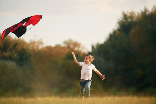 istock Little boy is playing outdoors at daytime. With red colored kite 1830204334